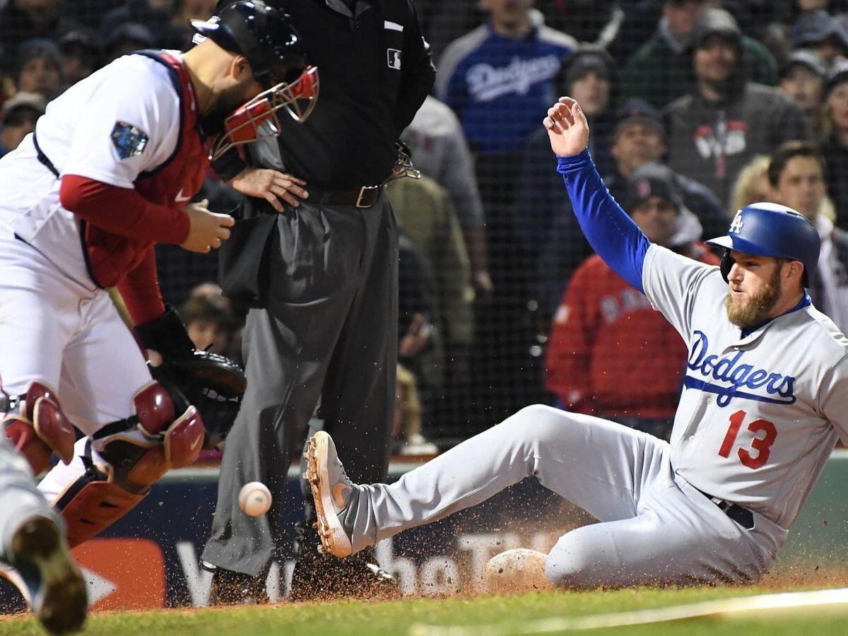 The Dodgers' Max Muncy scores on a sacrifice fly as Red Sox catcher Sandy Leon bobbles the ball.