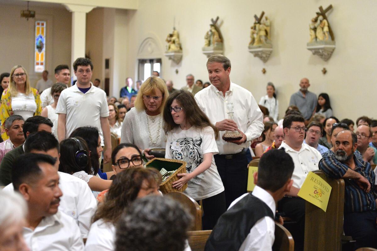 Tori Bayer, with parents Virginia and Rob, collect donations and bring up the wine and bread at the 2019 Mass of Inclusion.