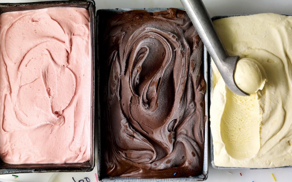 A photo of three different types of ice cream in black rectangular tubs.