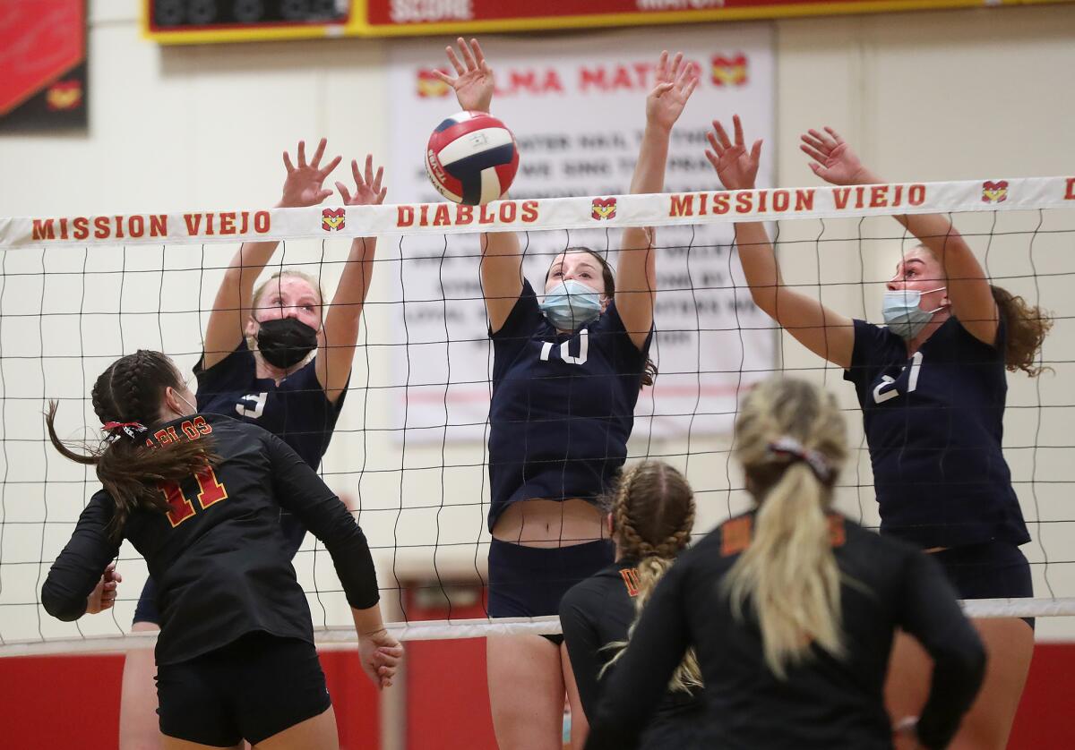 Newport Harbor's Anne O'Brien (10) blocks a kill by Anna Bolich (11) with help from Emma Coatsworth (9) and Emma Fults (27).