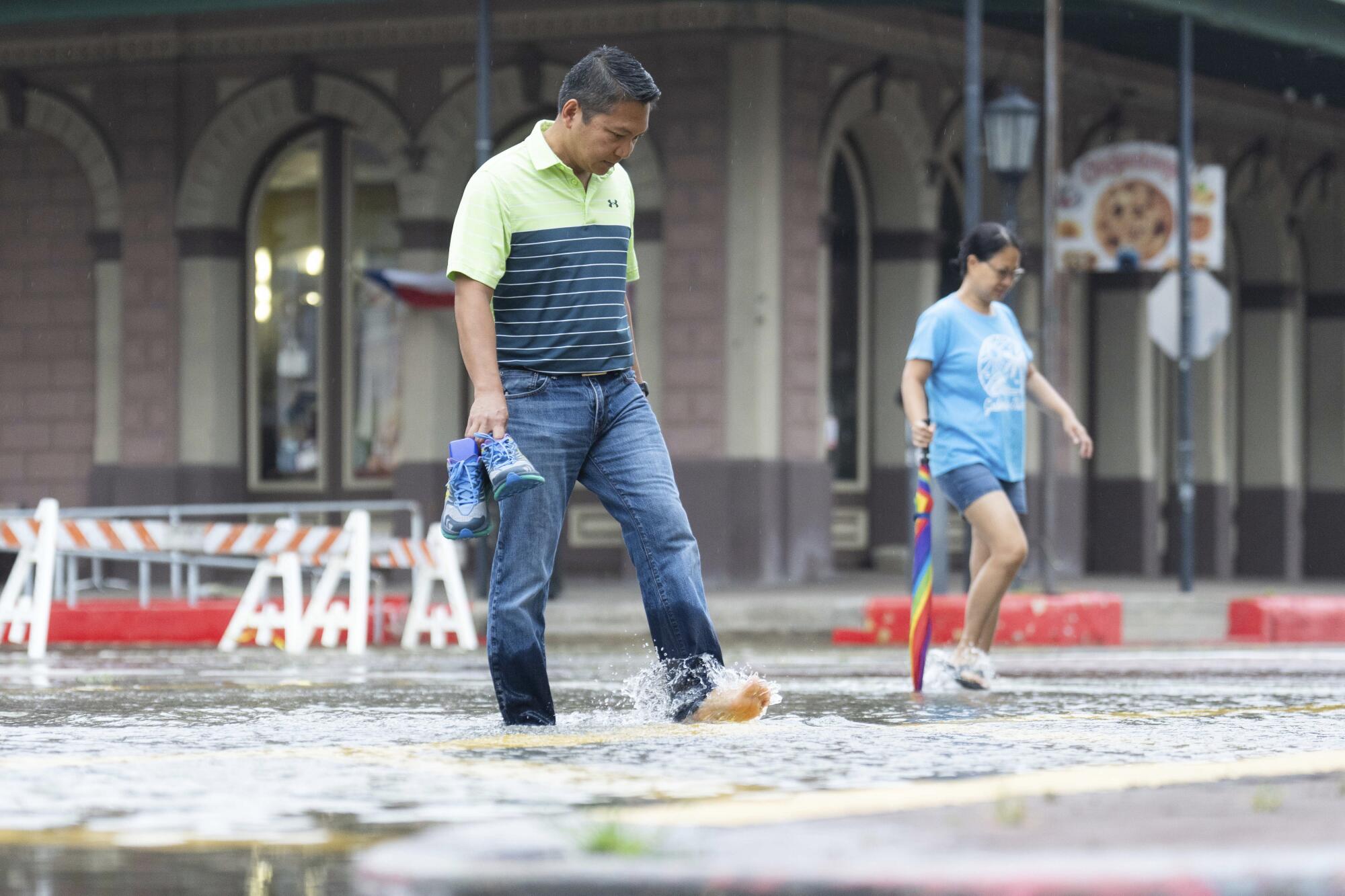 Roy Quiroz y su esposa, Minda, caminan por una calle inundada mientras llueve 