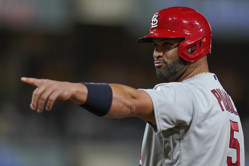 St. Louis Cardinals' Albert Pujols jokes with players in the San Diego Padres' dugout.