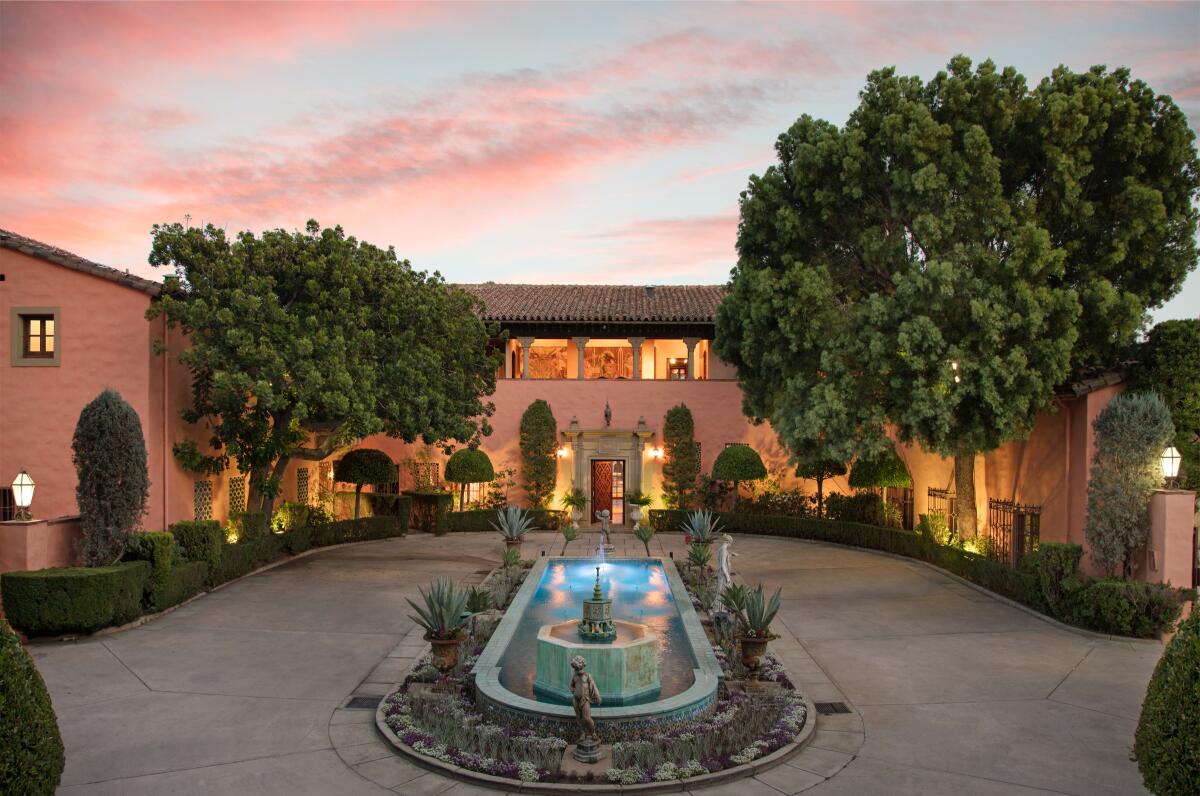 The Mediterranean Revival-style mansion with a fountain in front.