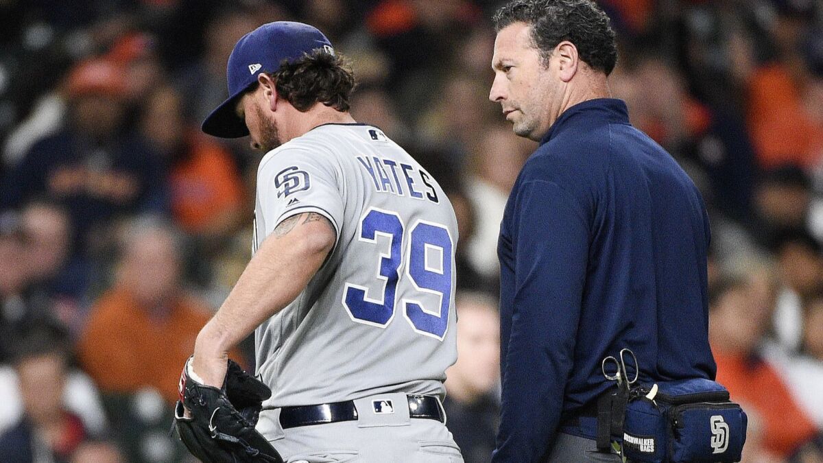 Padres relief pitcher Kirby Yates, left, walks to the dugout with a trainer after a pitch during the eighth inning of a baseball game against the Houston Astros, Saturday, April 7, 2018, in Houston.