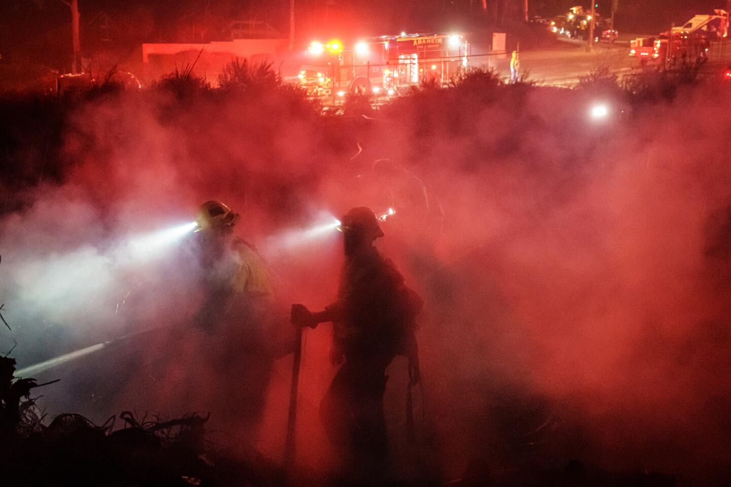 Firefighters mop up after stopping the progress of the Castlewood fire in Fullerton.