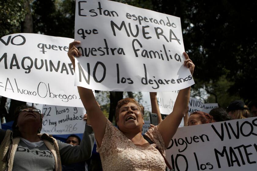 Family members holding signs that read in Spanish "They are waiting for our family to die," "They are still alive. Don't kill them" and "No heavy machinery," protest outside a quake-collapsed seven-story building in Mexico City's Roma Norte neighborhood, Friday, Sept. 22, 2017. They are protesting because they believe that authorities are abandoning the search and will bring in heavy machinery to remove the rubble, extinguishing any hopes of finding their loved ones alive. (AP Photo/Rebecca Blackwell)