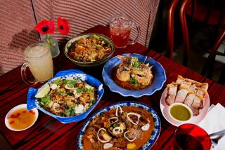 LOS ANGELES, CA - AUGUST 7, 2024: A feast of Holy Basil's signature dishes, including (clockwise from top) Papaya Salad, Soft Shell Crab with Salted Yolk, Moo Krob, Penang Short Rib, and Grandma's Fish and Rice. (Jennelle Fong / For The Times)