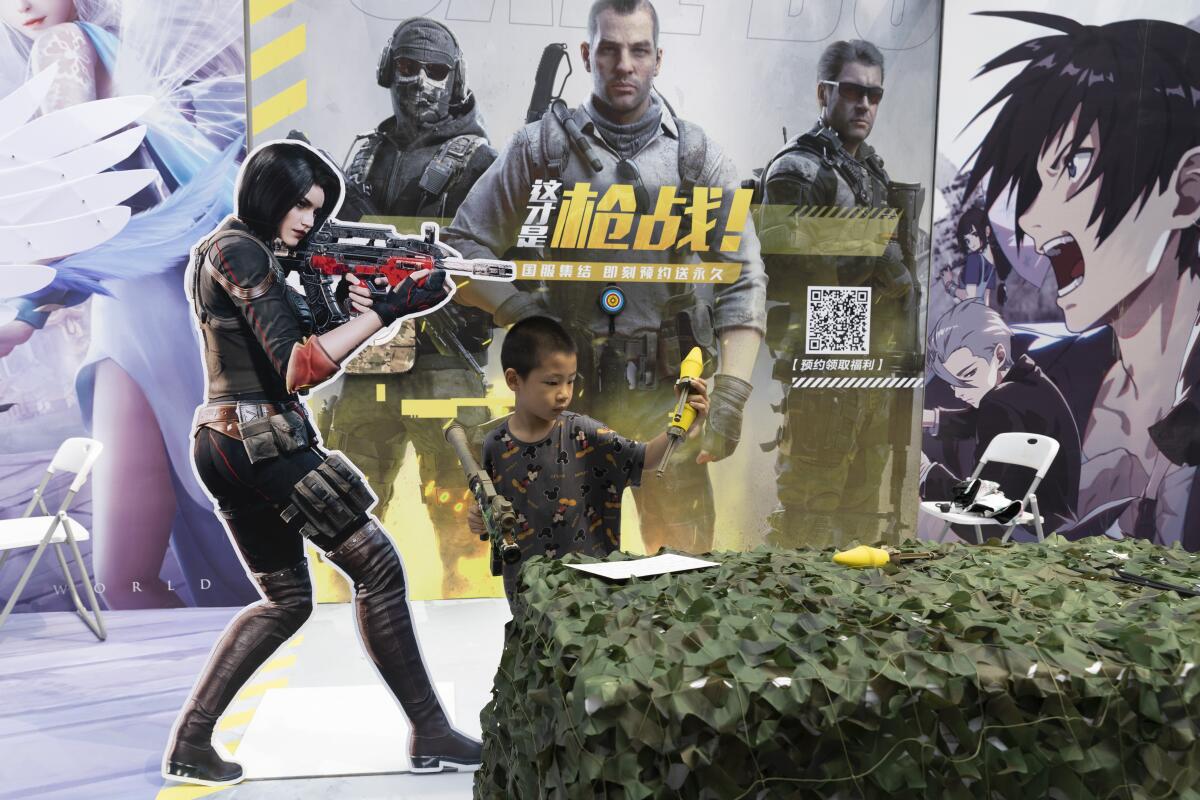 A child holding a toy gun behind a bush, in front of various video game characters