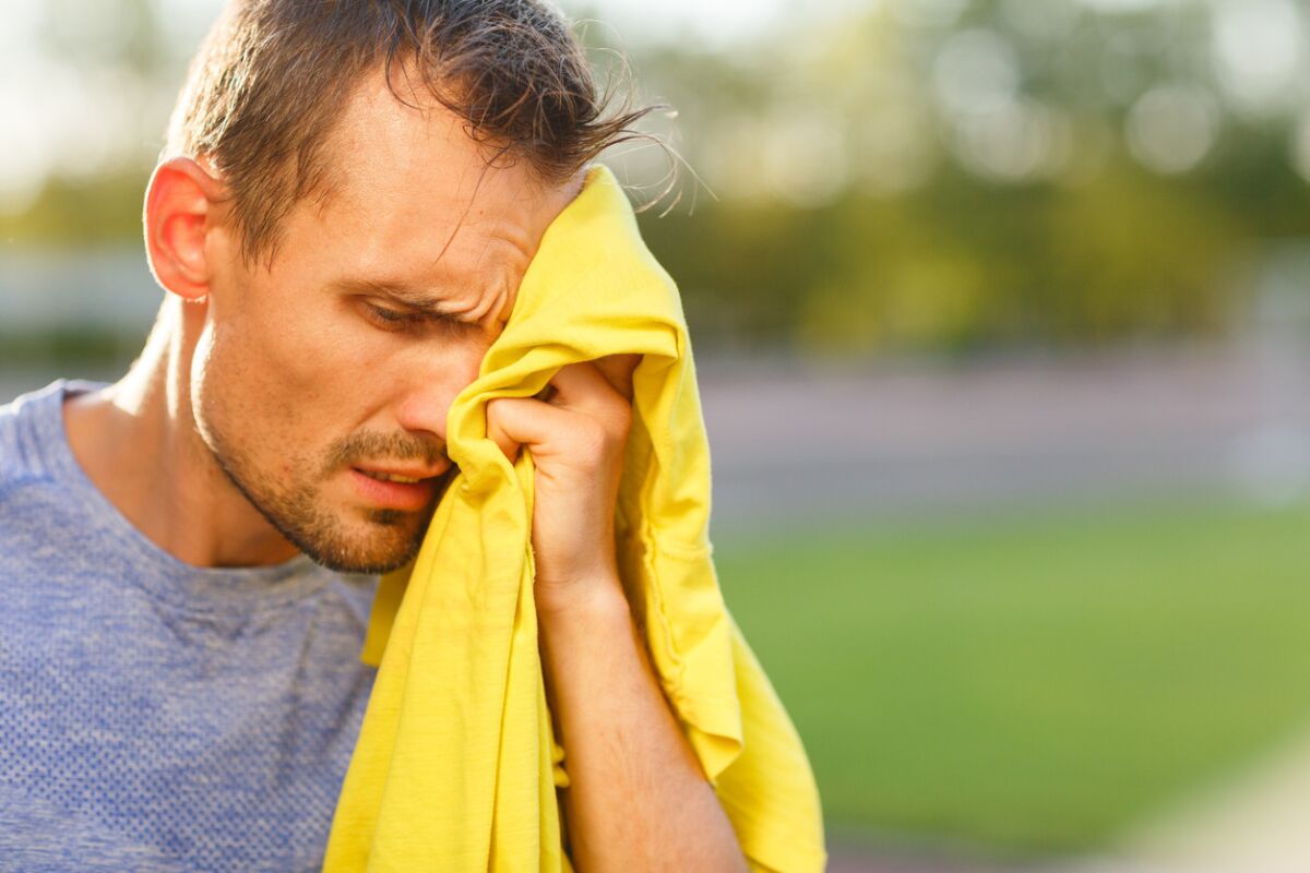 Athletic man wipes his face with yellow towel after training outdoor