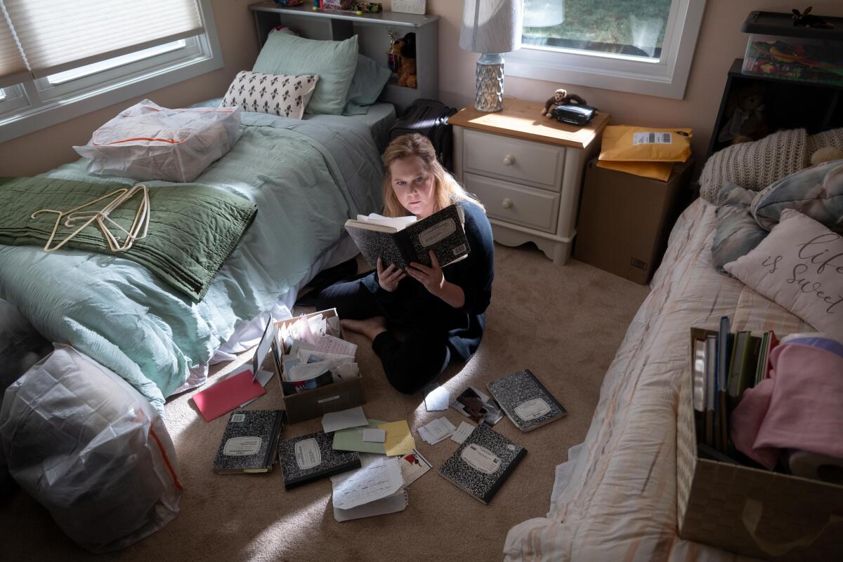 A woman sitting on the floor of her childhood bedroom, reading newspapers in a scene from "Life and Beth."