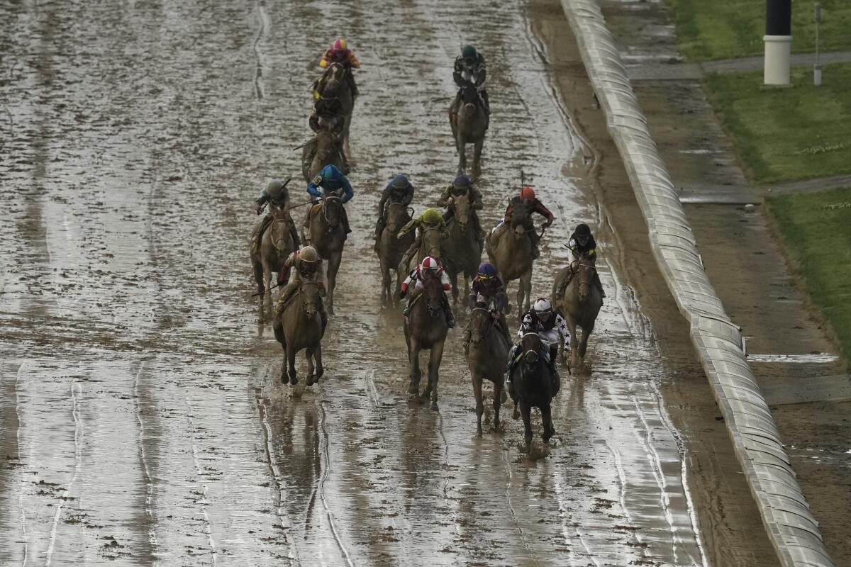 Horses run on a muddy track during the 150th running of the Kentucky Oaks horse race Friday.