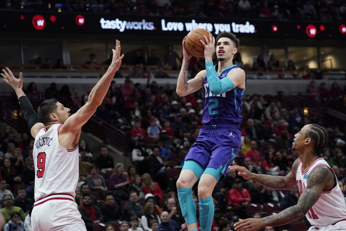Charlotte Hornets guard LaMelo Ball, center, drives to the basket against Chicago Bulls center Nikola Vucevic, left, and forward DeMar DeRozan during the first half of an NBA basketball game in Chicago, Friday, April 8, 2022. (AP Photo/Nam Y. Huh)