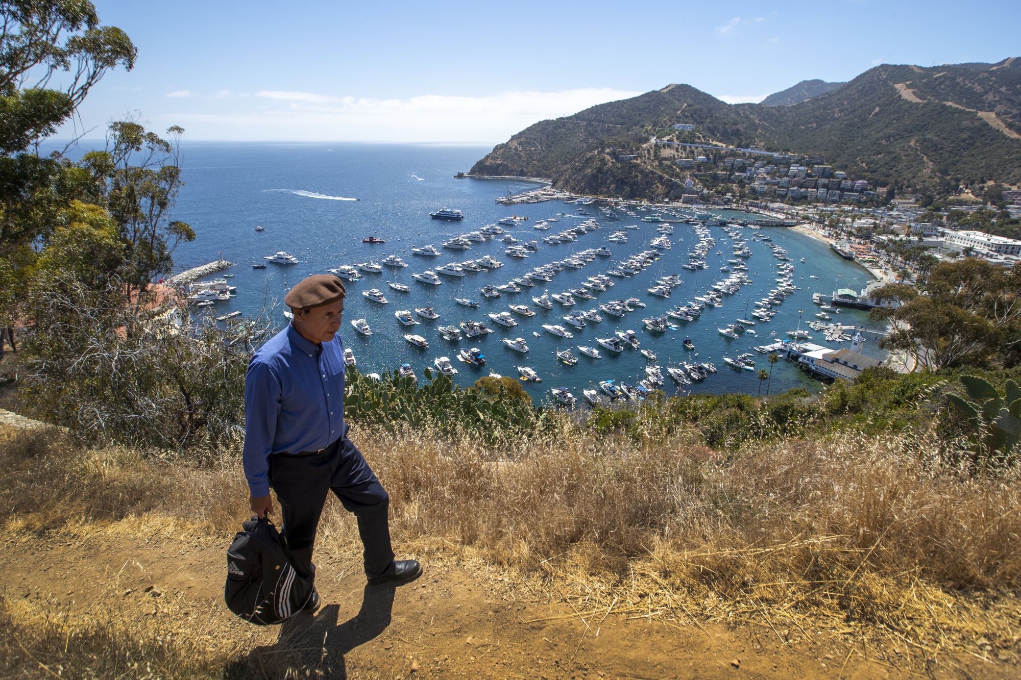 Chicano activist David Sanchez, wearing the signature brown beret, hikes on Catalina Island to the site of 1972 protest camp
