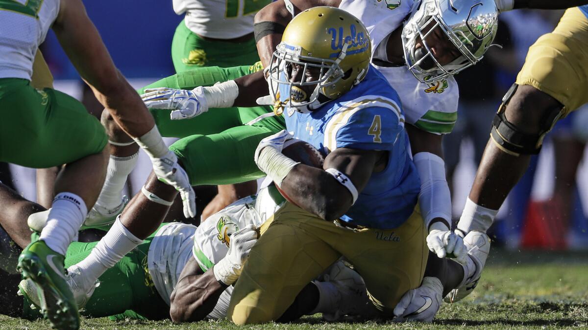 UCLA running back Bolu Olorunfunmi, tackled by Ducks defenders after a gain during the fourth quarter Saturday, finished with a team-high 76 yards in 13 carries.