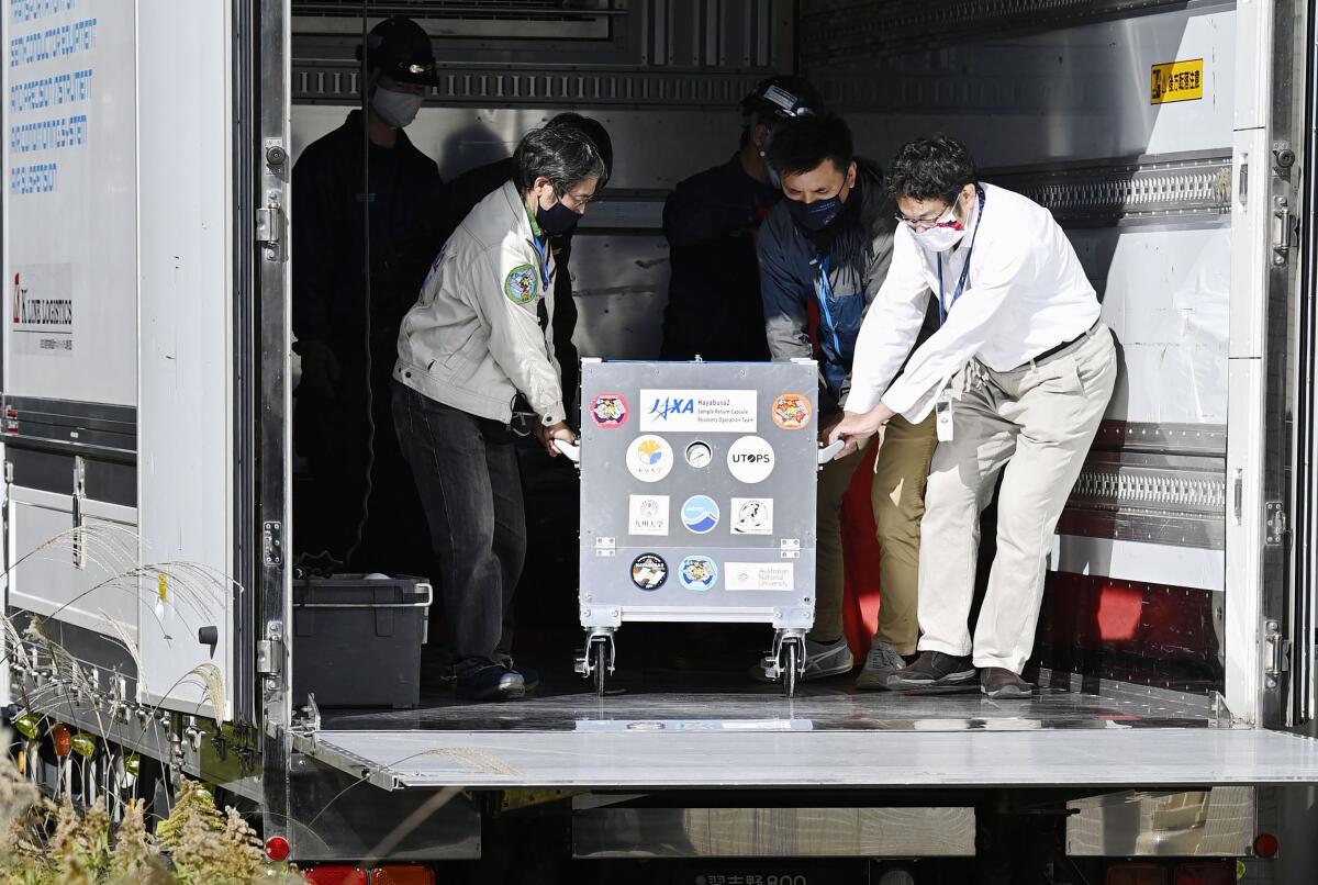A small capsule dropped by Japans' Hayabusa2 spacecraft in a container box arrives at the Japan Aerospace Exploration Agency's research facility in Sagamihara, near Tokyo Tuesday, Dec. 8, 2020. The capsule containing asteroid soil samples that landed in the Australian Outback arrived Tuesday in Tokyo for research into the origin of the solar system and life on Earth. (Yu Nakajima/Kyodo News via AP)