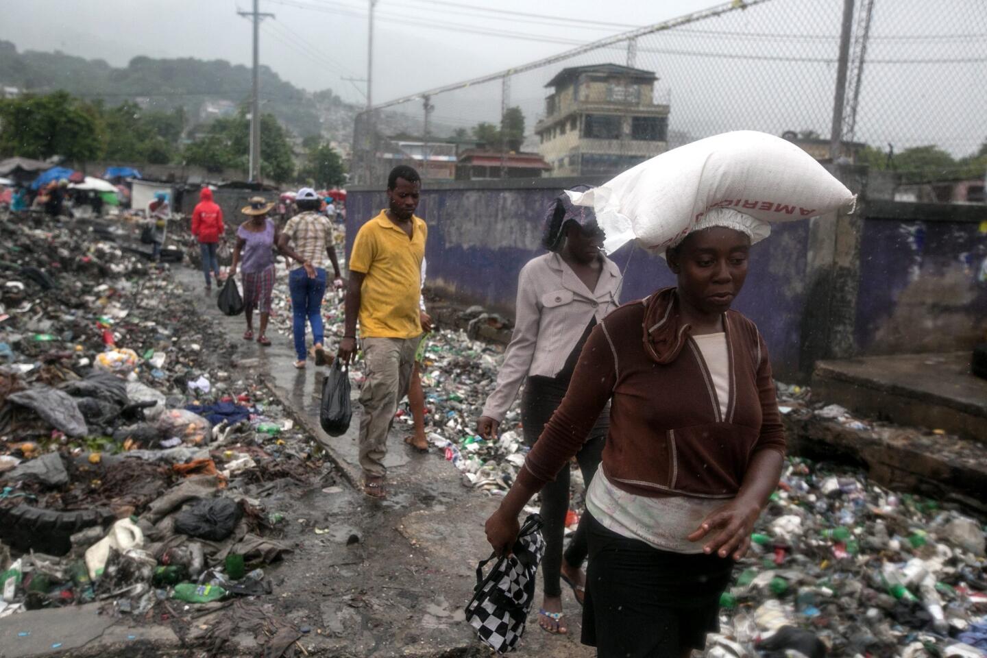 Residents walk through a garbag-filled street in Port-au-Prince, Haiti, on Oct. 4, 2016.