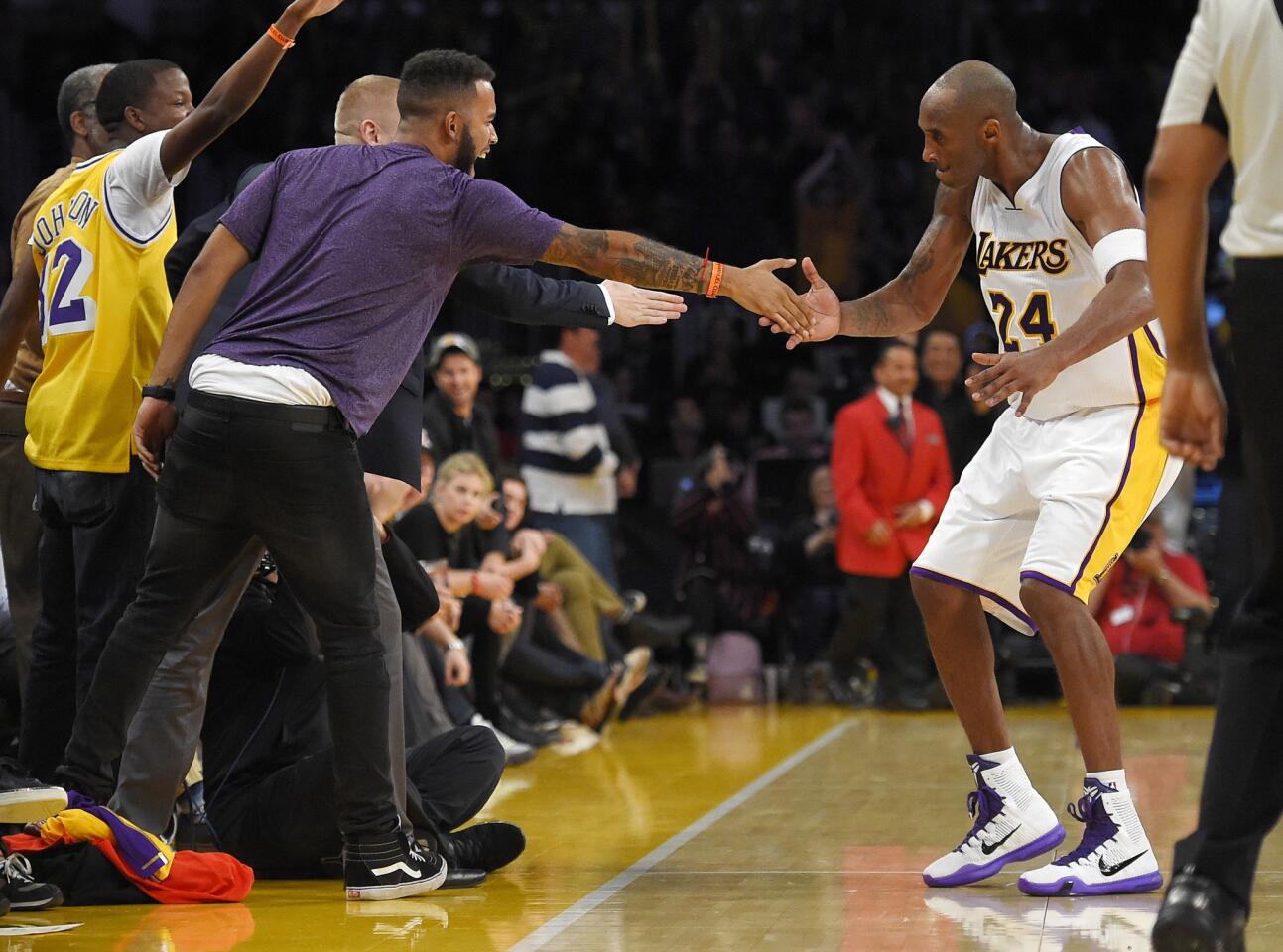 Los Angeles Lakers forward Kobe Bryant, right, celebrates with Anthony Sadler, front left and Spencer Stone, obscured, after hitting a 3-point shot during the second half of an NBA basketball game against the Detroit Pistons, Sunday, Nov. 15, 2015, in Los Angeles. Sadler, and Stone are two of three Americans who helped stop a terrorist attack on a train in France in August. The Lakers won 97-85. (AP Photo/Mark J. Terrill)