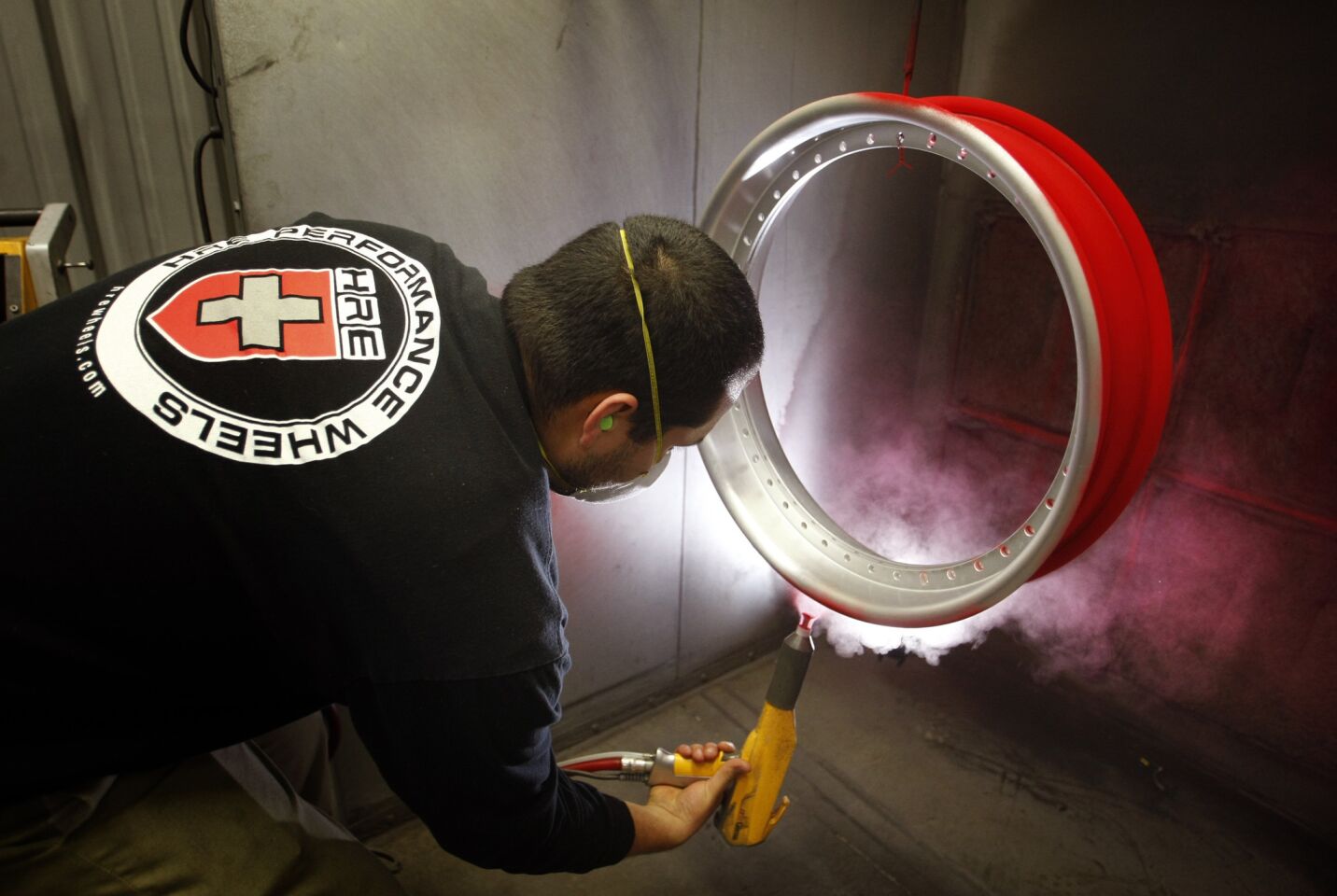 Sammy Hermosillo coats an aluminum rim with red powder before it's baked to a hard, glossy surface.