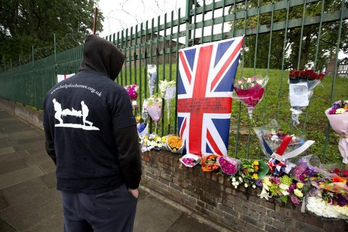 A man wearing a Help the Heroes jacket pauses at the makeshift memorial erected at the site where soldier Lee Rigby was killed outside Woolwich Barracks in London. Help the Heroes is a British charity for wounded soldiers.