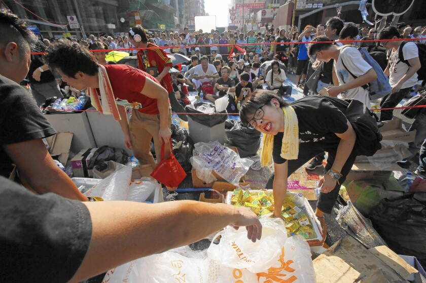 A protester reaches for a cold drink in Hong Kong. A vast supply of donated goods is keeping the demonstrators comfortable.