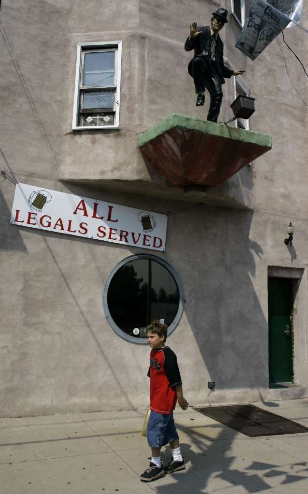 A boy walks past a bar in Hazleton, Pa., as it displays a sign on that reads "ALL Legals Served." The city is asking the U.S. Supreme Court to review lower-court decisions that invalidated its 2006 ordinance discouraging the hiring or housing of undocumented immigrants.