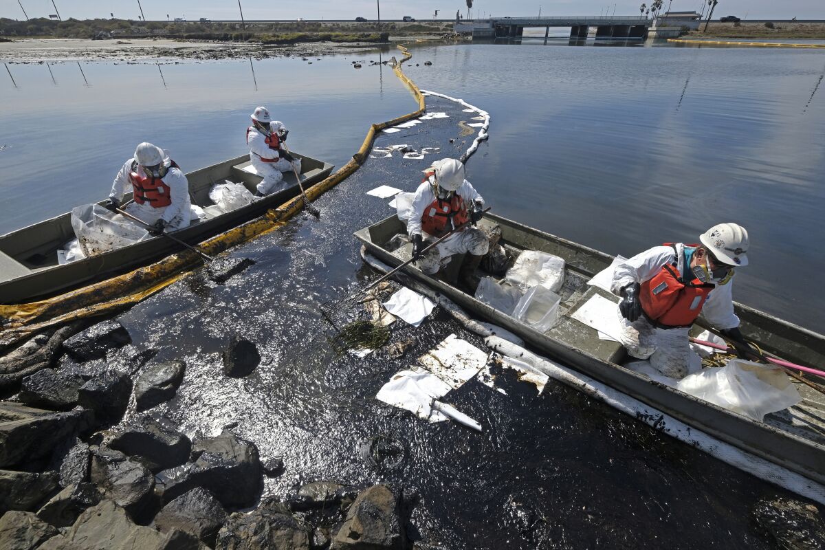 Cleanup contractors deploy skimmers and floating barriers known as booms to try to stop further oil crude incursion into the Wetlands Talbert Marsh in Huntington Beach, Calif., Sunday, Oct. 3, 2021. (AP Photo/Ringo H.W. Chiu)