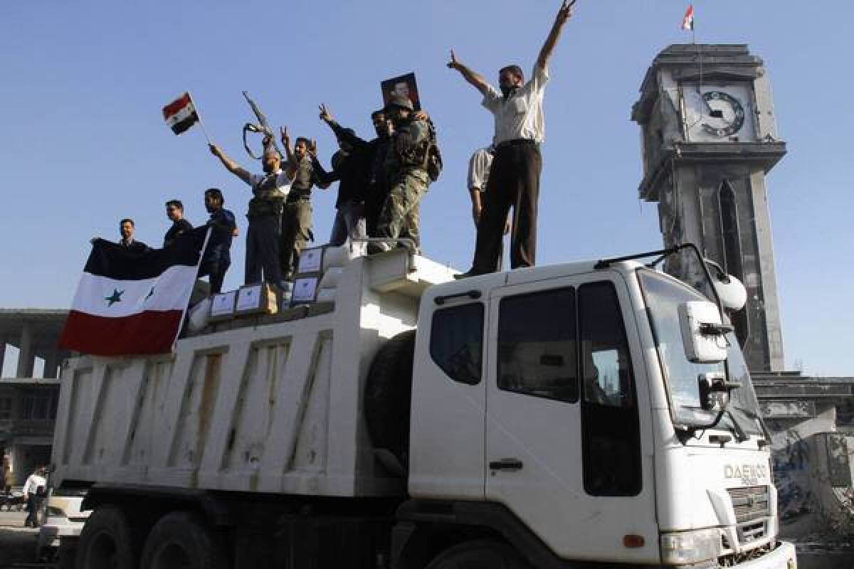 Forces loyal to the Syrian army celebrate as they drive through the main square of Qusair after helping President Bashar Assad's soldiers retake control of the area this month.