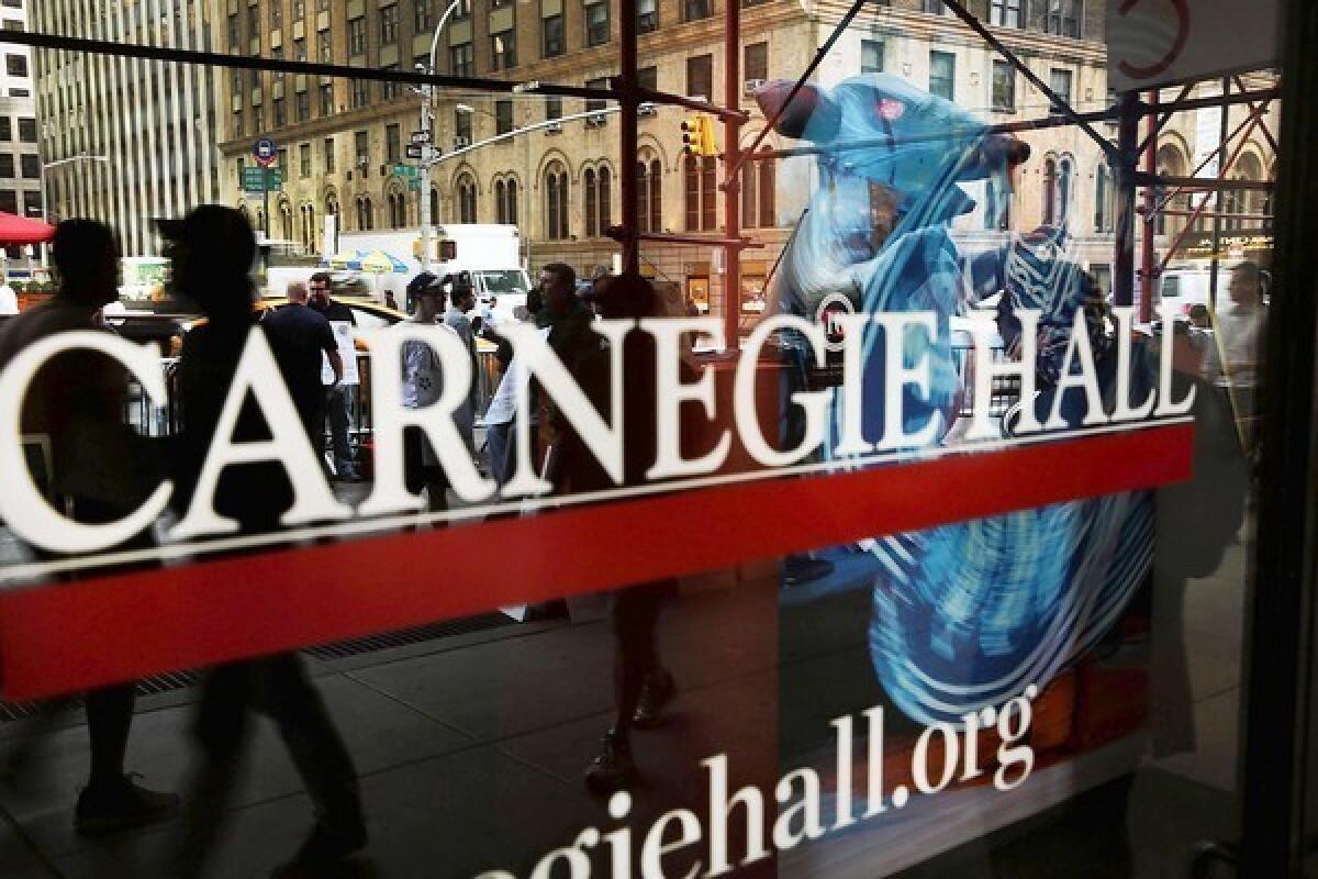 Members of Local 1 International Alliance of Theatrical Stage Employees are reflected in a window as they picket outside of Carnegie Hall.