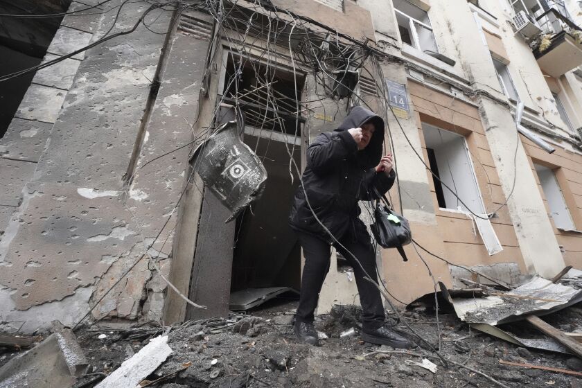 Una mujer sale de un edificio residencial que fue impactado por un cohete ruso, en la ciudad de Járkiv, Ucrania, el domingo 5 de febrero de 2023. (AP Foto/Andrii Marienko)
