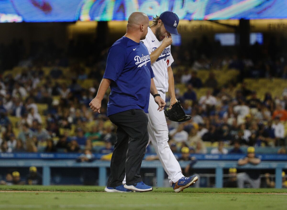 Clayton Kershaw walks off the mound with trainer Neil Rampe  on Friday night.