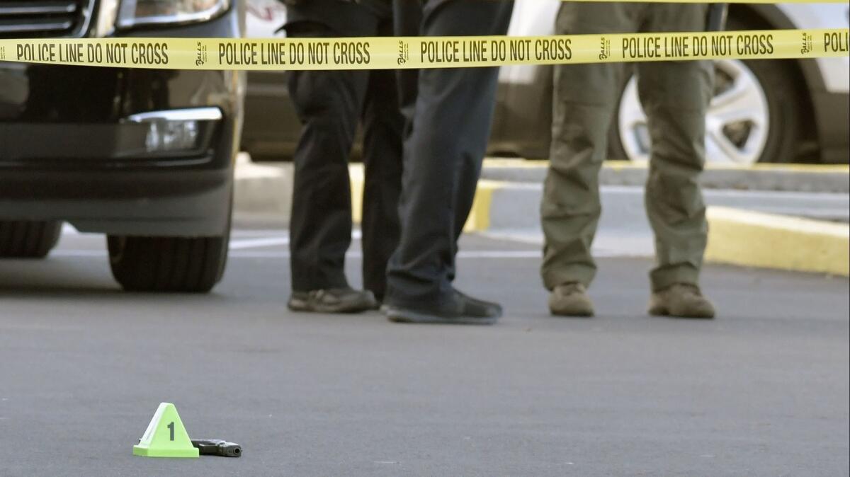 A gun lies on the ground after a shooting at a Kroger grocery in Louisville that left two African Americans dead. The suspect later stated, "Whites don't kill whites."