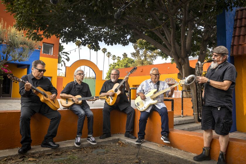 Los Angeles, CA - July 22: Los Lobos: left to right: Cesar Rosas, singer, songwriter and guitarist, Louie Perez, songwriter, percussionist and guitarist, David Hidalgo, singer-songwriter, accordion, violin, 6-string banjo, cello, requinto jarocho, percussion, drums and guitar, Conrad Lozano, bass, and Steve Berlin, saxophonist, keyboardist and record producer, are photographed at Plaza de la Raza on Thursday, July 22, 2021 in Los Angeles, CA. Archetypal LA band Los Lobos will release Native Sons, which features their version of classic L.A. songs including Sail On, Sailor (Beach Boys), The World Is A Ghetto (WAR) and Flat Top Joint (The Blasters). Now in their 40th year as a band, Los Lobos shoots a video for the National Endowment for the Arts at Plaza de la Raza in Lincoln Heights. (Allen J. Schaben / Los Angeles Times)