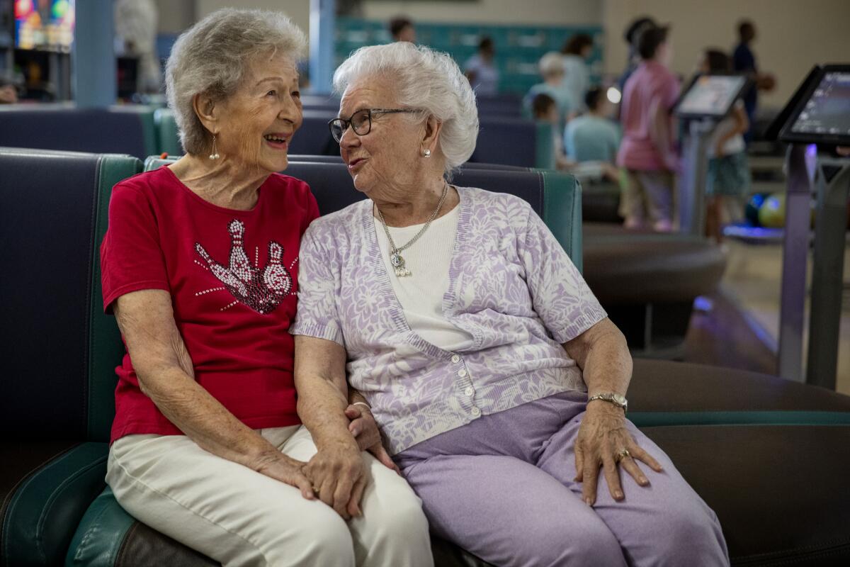 Lillian Solomon, a la izquierda, conversa junto con la jugadora de bolos Elaine Allen, de 87 años, entre juegos, durante su noche de liga.