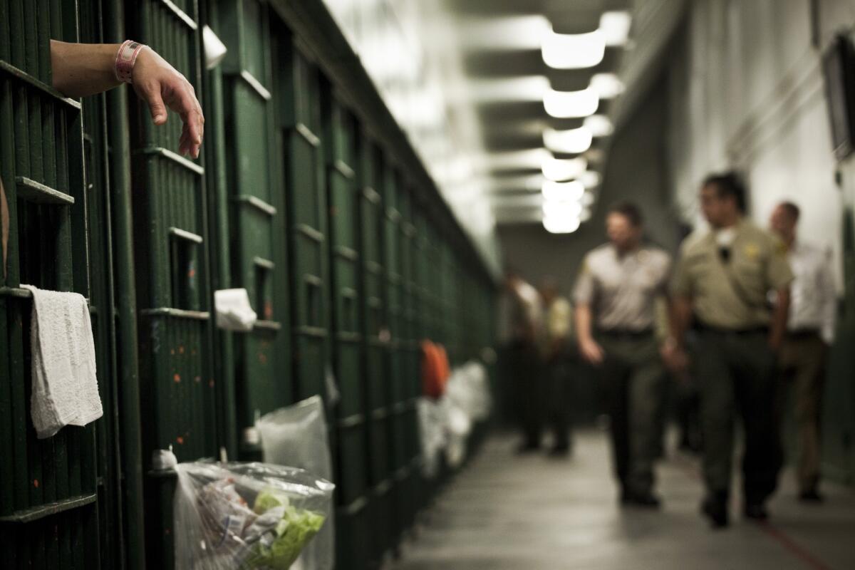 Deputies walk past cells at the L.A. County Men's Central Jail. County jails house 19,000 inmates.