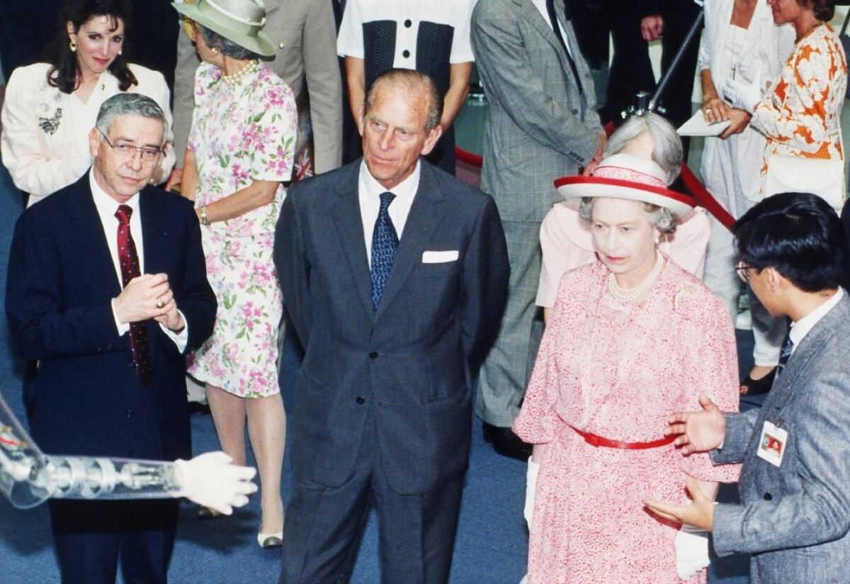 The robot hand appears to be reaching out to Queen Elizabeth and Prince Philip during their 1983 Johnson Space Center visit.