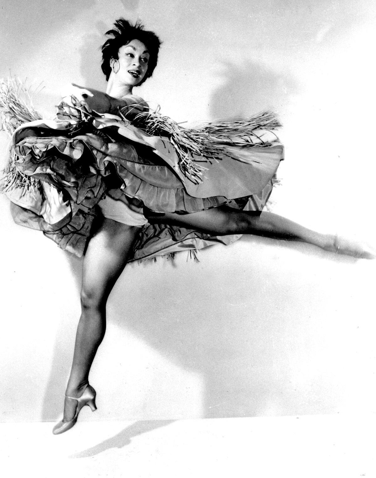 A black and white photo shows performer Chita Rivera, mid leap, her skirts fluttering all around her.