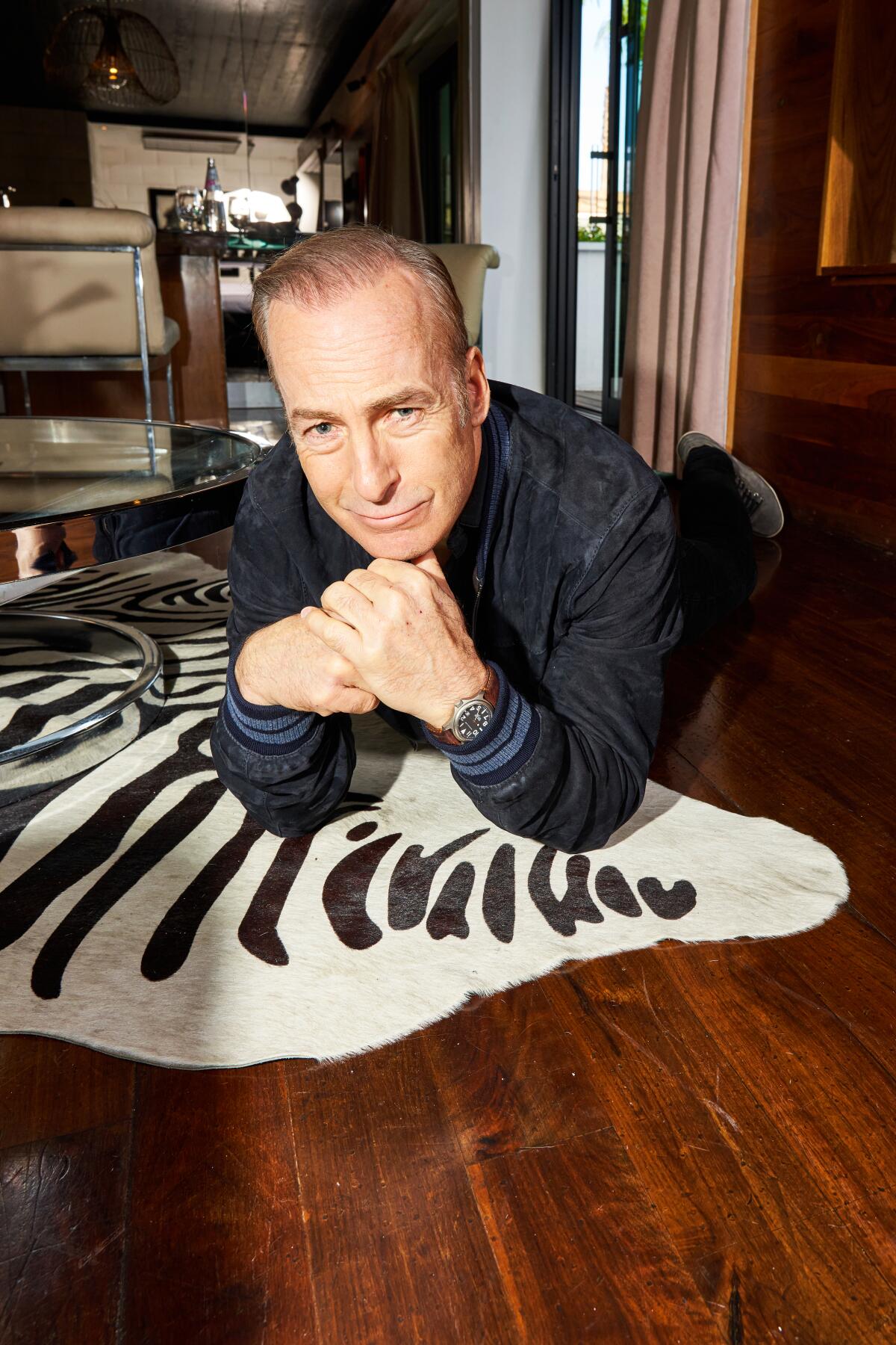 Bob Odenkirk lies on a faux zebra-skin rug for a portrait.