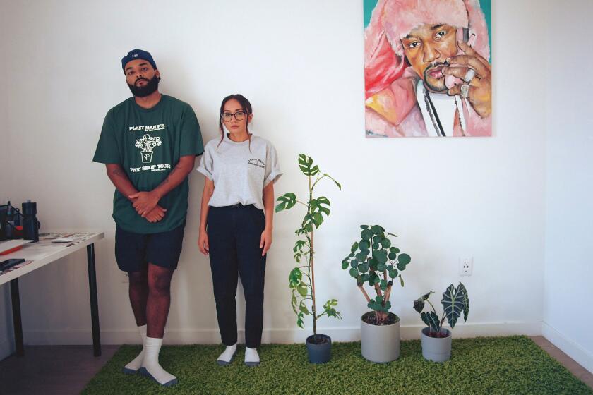 Jon Perdomo and Jerrilyn Peralta take a family portrait with their plants in a row next to a Cam'ron painting