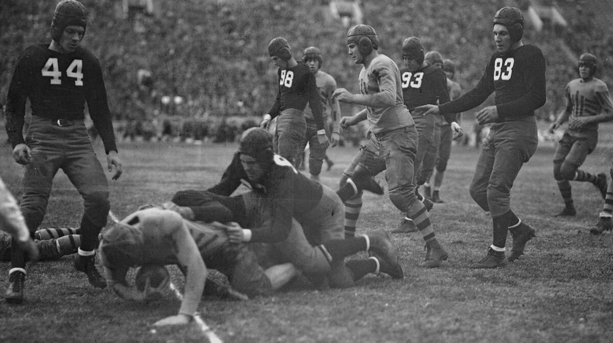 Young men play football. They wear leather helmets, jerseys with small shoulder pads, and ankle-high cleats.