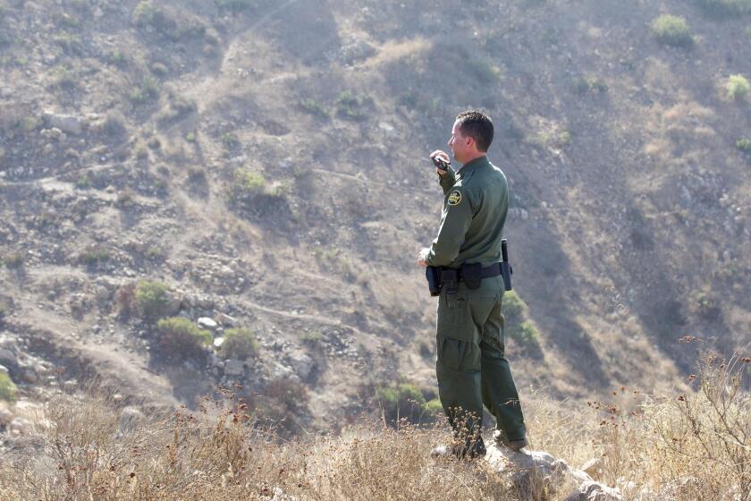 US Border Patrol Agent Theron Francisco looked off in to the Otay Mountain Wilderness Area where the border fence will be constructed in the coming year, at the US-Mexico Border east of Otay Mesa in San Diego on Tuesday, October 15, 2019. You can see the paths worn in to the hillside by people entering in to the US illegally.