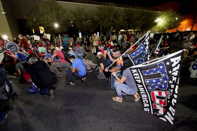 President Donald Trump supporters kneel as they rally, Wednesday, Nov. 4, 2020, outside the Maricopa County Recorders Office in Phoenix. (AP Photo/Matt York)