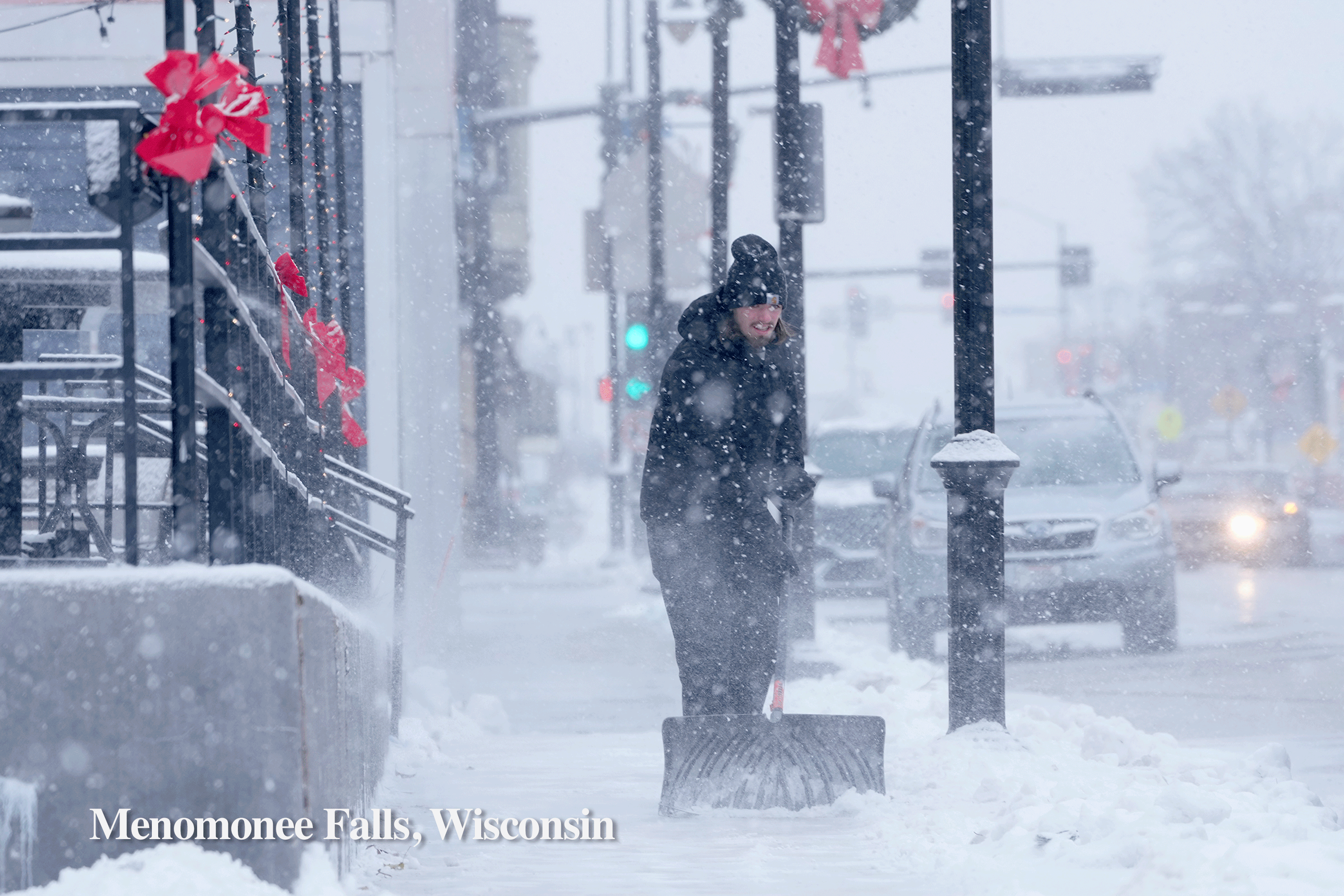 A person shovels snow in Menomonee Falls, Wisconsin, as opposed to a person along the shoreline in Long Beach.
