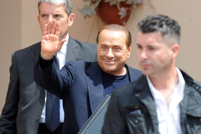 Former Italian Prime Minister Silvio Berlusconi waves as he leaves the Fondazione Sacra Famiglia on Friday in Milan.