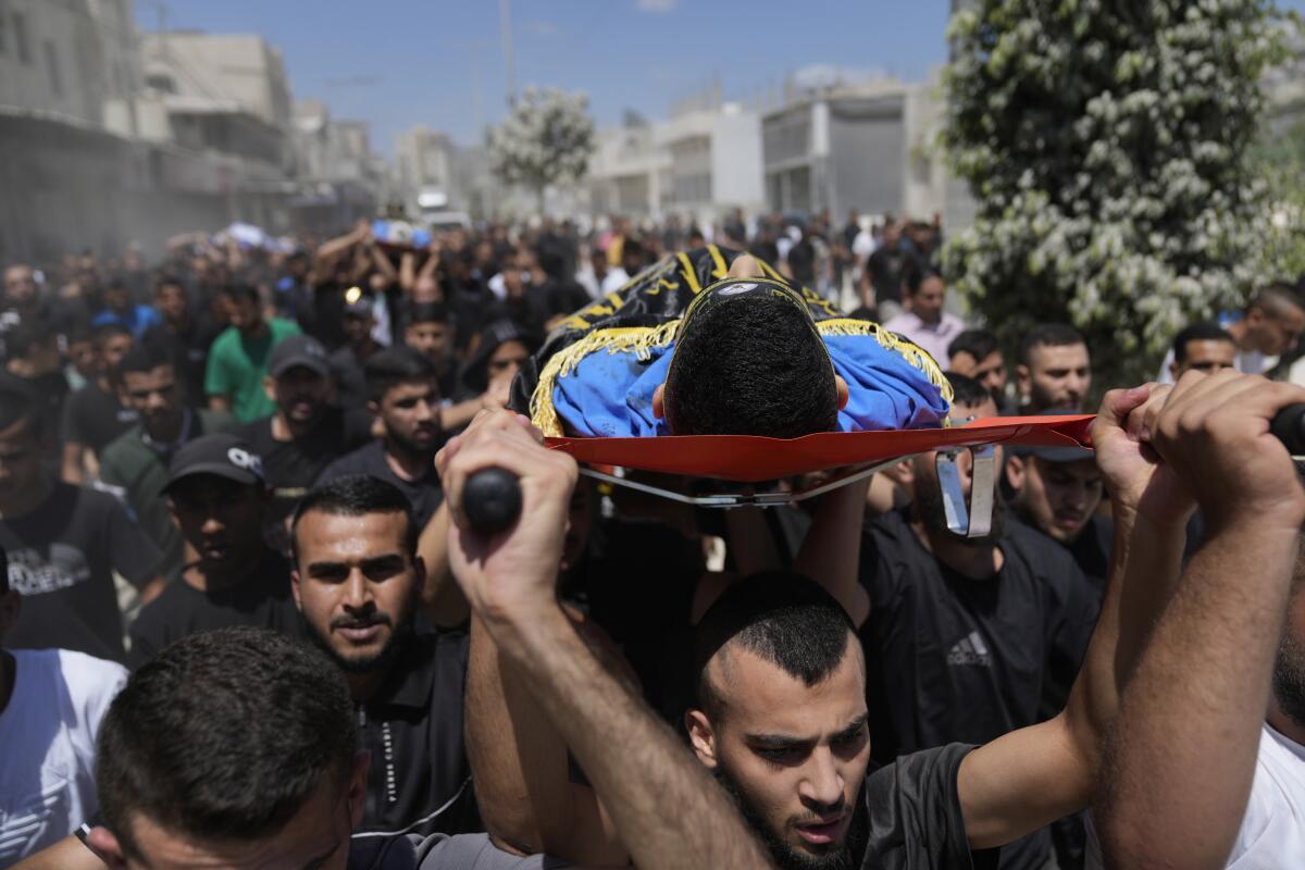 Mourners carry the bodies of four Palestinians killed by an Israeli airstrike in the West Bank.