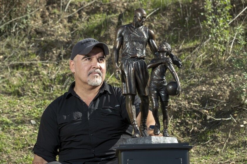 An artist with a statue depicting Kobe and Gianna Bryant