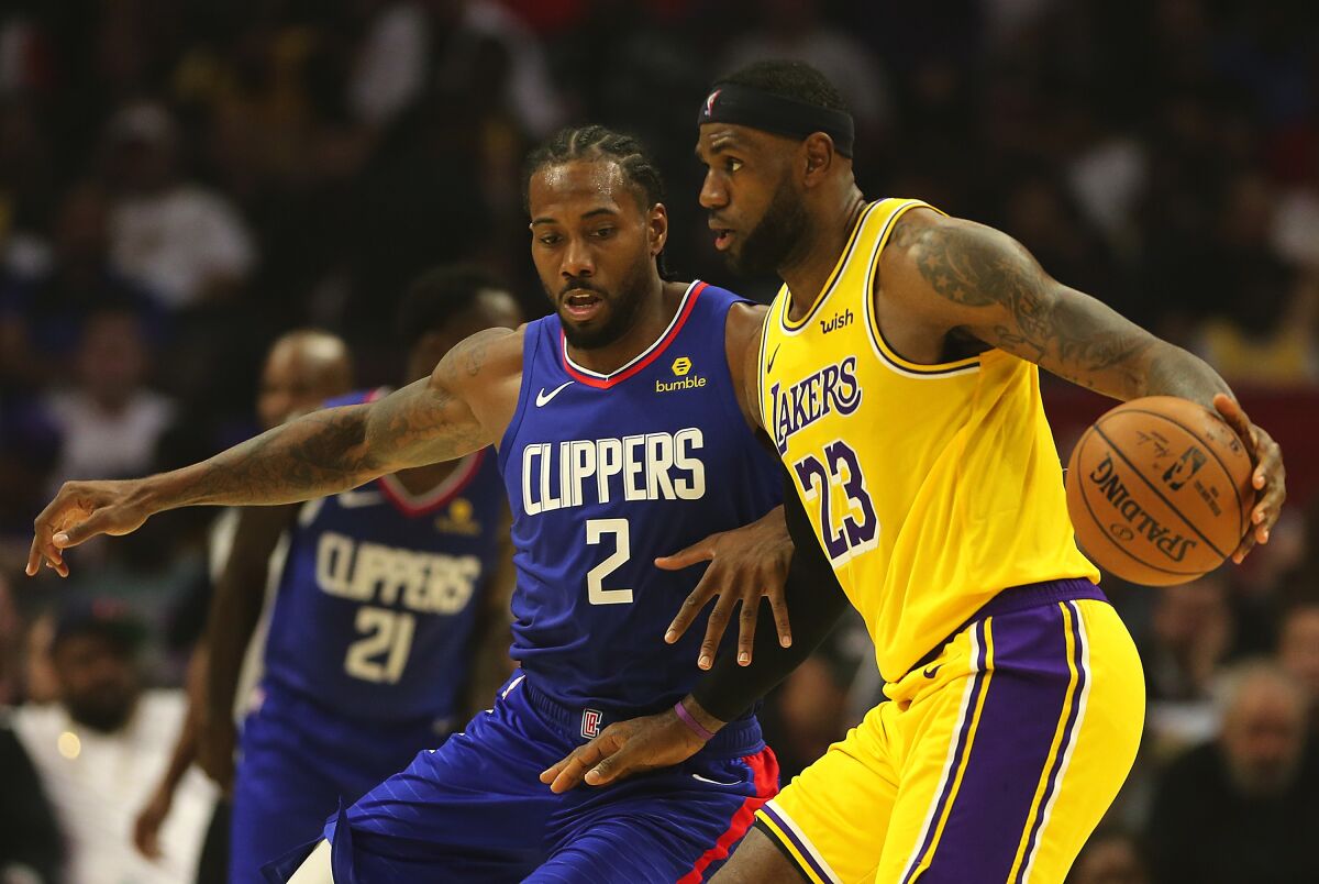 Lakers forward LeBron James, right, controls the ball in front of Clippers forward Kawhi Leonard.