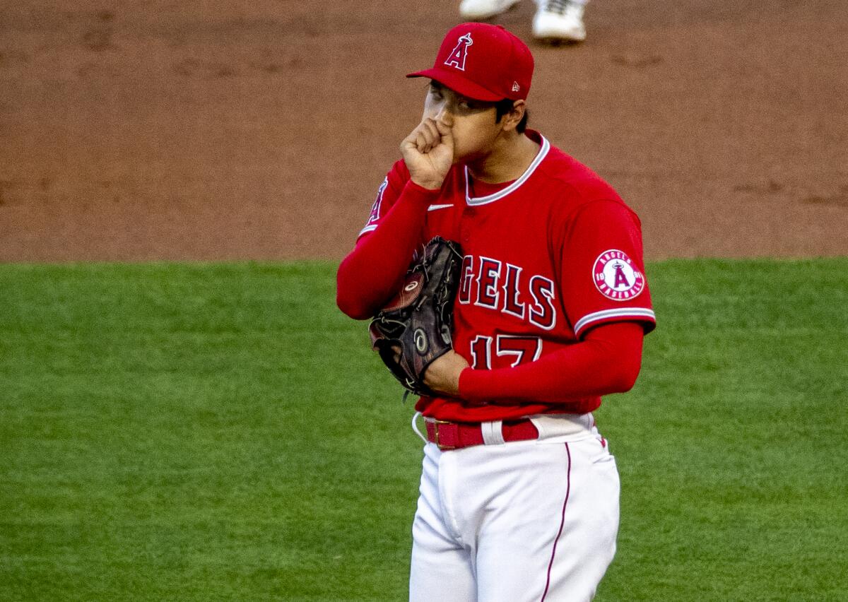 Angels pitcher Shohei Ohtani blows on his hand at the mound.