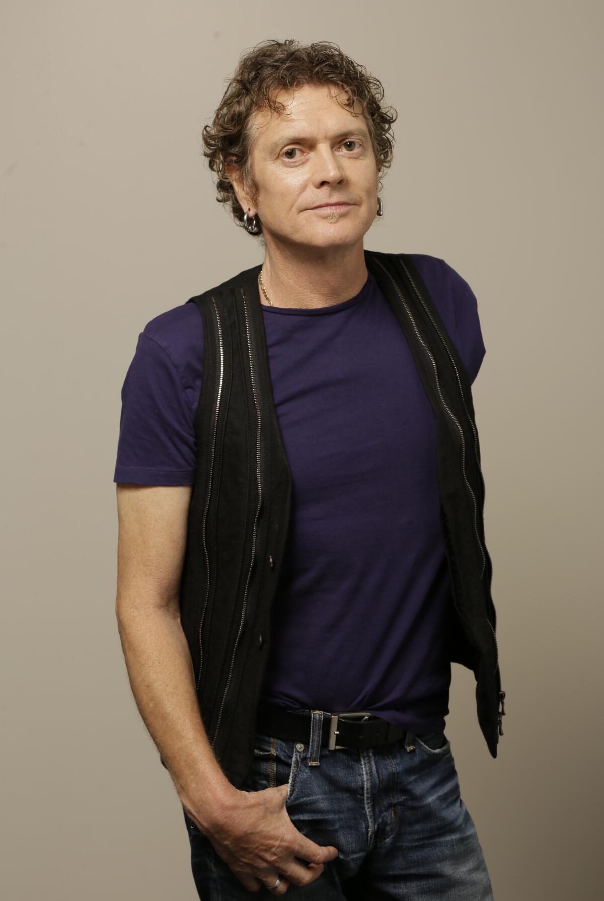 Def Leppard drummer Rick Allen  wearing a vest over a T-shirt and jeans, poses for a portrait