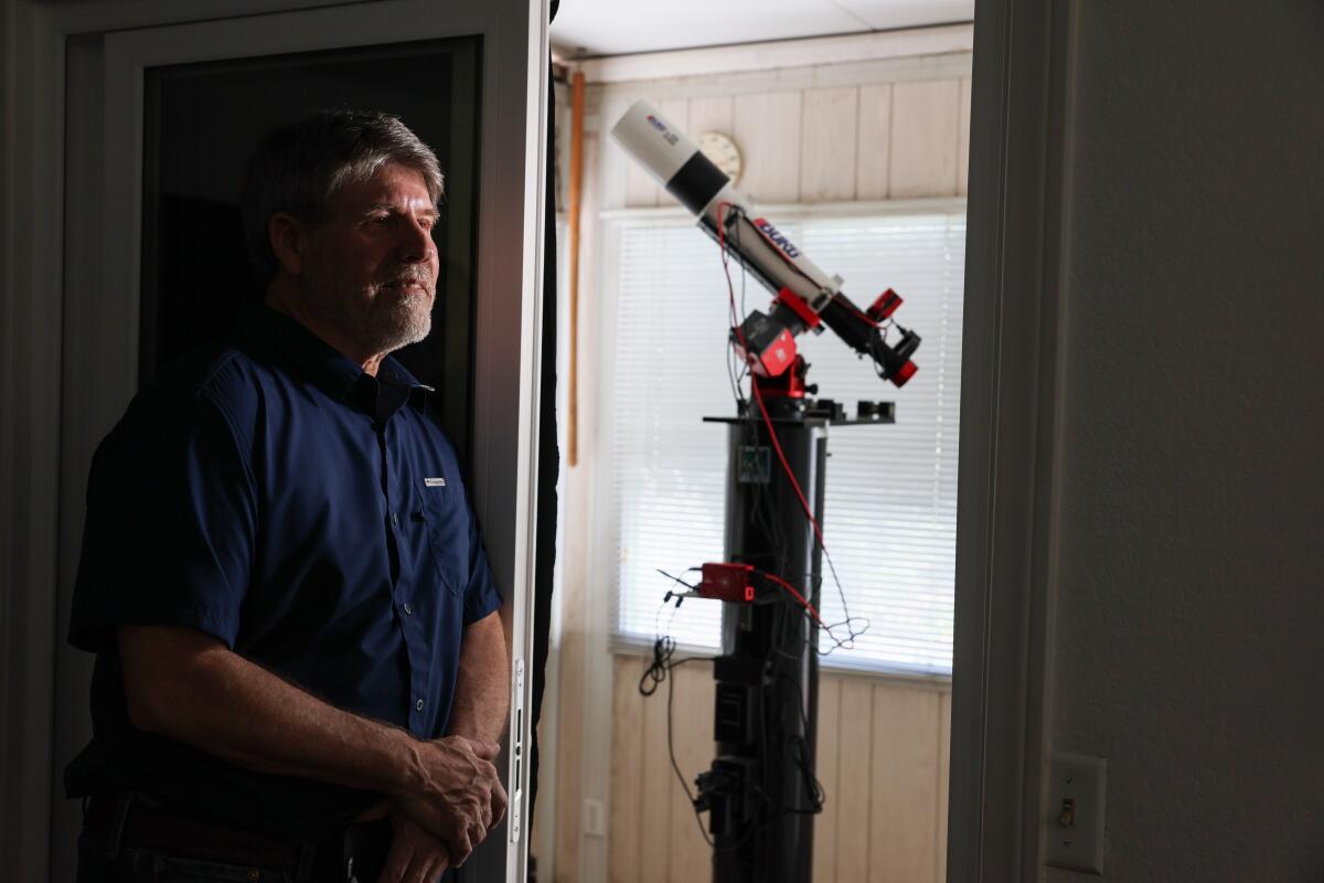 Bob Stephens stands beside a telescope at his Cucamonga home.