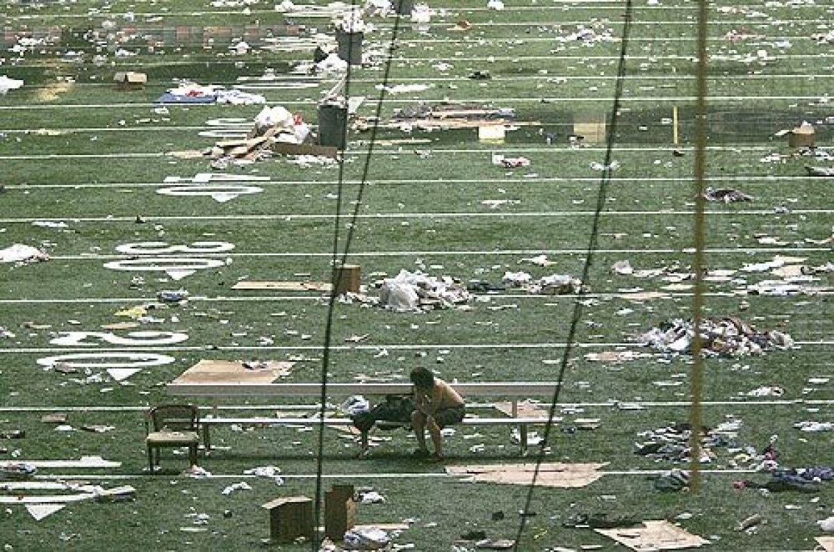 A lone evacuee rests on the dark and debris laden New Orleans Superdome field as Hurricane Katrina victims queue up to leave the Superdome, Thursday.